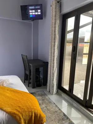 a bedroom with a bed and a table and a television at Morodi Guest Lodge in Witbank