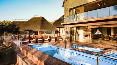 a large swimming pool in front of a house at Zebula 6 Bedroom Lodge IV2 in Warmbaths