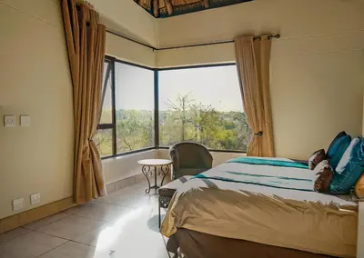a bedroom with a bed and a large window at Zebula 6 Bedroom Lodge IV2 in Warmbaths