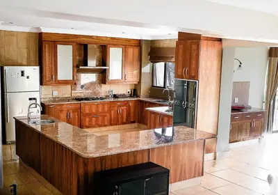 a large kitchen with wooden cabinets and a large island at Zebula 6 Bedroom Lodge IV2 in Warmbaths
