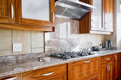 a kitchen with wooden cabinets and a stove top oven at Zebula 6 Bedroom Lodge IV2 in Warmbaths