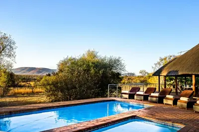 a swimming pool with chairs and a gazebo at Zebula 6 Bedroom Lodge IV2 in Warmbaths