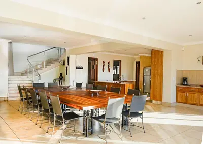 a dining room with a wooden table and chairs at Zebula 6 Bedroom Lodge IV2 in Warmbaths