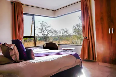 a bedroom with a bed and a large window at Zebula 6 Bedroom Lodge IV2 in Warmbaths