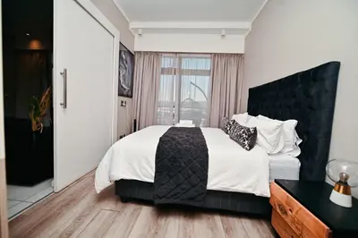 a bedroom with a large bed with a black headboard at Menlyn Maine Apartment with Sunbet Casino view in Pretoria