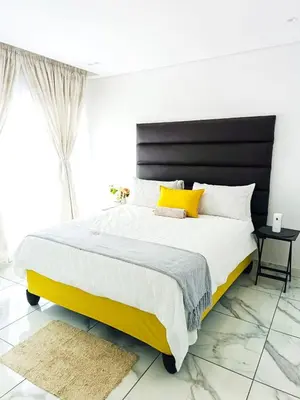 a bedroom with a large bed with yellow and white pillows at Eden Groove Luxury self catering Guesthouse in Matsulu