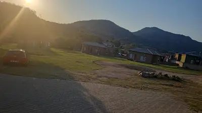 a car parked in a field with mountains in the background at Eden Groove Luxury self catering Guesthouse in Matsulu