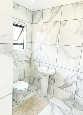 a white bathroom with a toilet and a sink at Eden Groove Luxury self catering Guesthouse in Matsulu