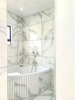 a white bathroom with a tub and marble walls at Eden Groove Luxury self catering Guesthouse in Matsulu