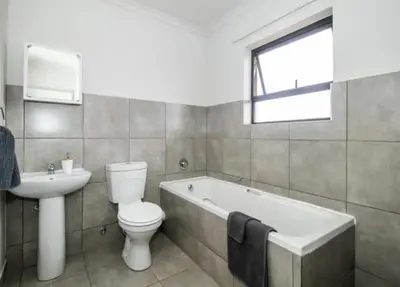a bathroom with a toilet and a sink and a bath tub at Tranquil Willows in Pretoria