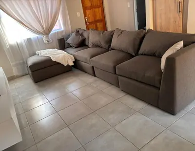 a brown couch in a living room with a tile floor at Tranquil Willows in Pretoria