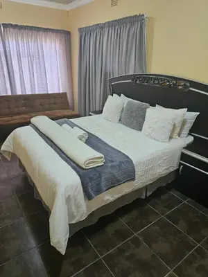 a bedroom with a large bed with white sheets and pillows at MATSOP Guesthouse in Bela-Bela