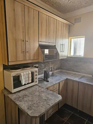 a kitchen with wooden cabinets and a white microwave at MATSOP Guesthouse in Bela-Bela