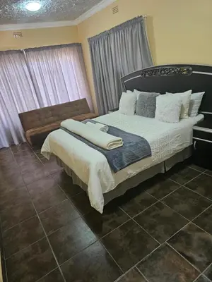 a bedroom with a large bed with white sheets and pillows at MATSOP Guesthouse in Bela-Bela