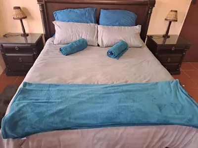 a bed with two blue pillows on it with two lamps at Ithiliens Grace Guesthouse in Pretoria