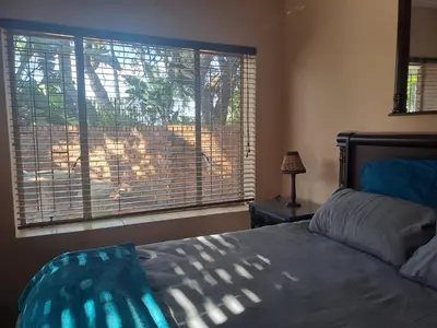 a bedroom with a bed and a window with a lion outside at Ithiliens Grace Guesthouse in Pretoria