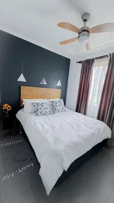 a bedroom with a white bed with a ceiling fan at Serenity suite in Midrand