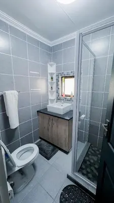a bathroom with a shower and a toilet and a sink at Serenity suite in Midrand