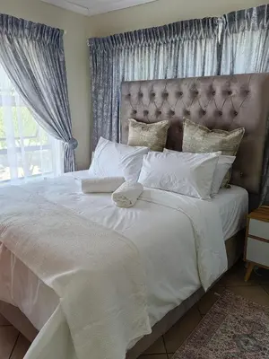 a bedroom with a large white bed with a large window at The Crown in Nelspruit