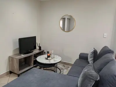 a living room with a blue couch and a tv at The Crown in Nelspruit