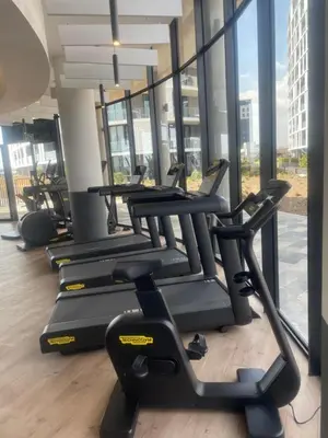 a row of treadmills in a gym with large windows at Chic & Elegant at Ellipse in Midrand