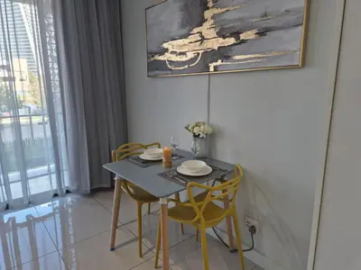 a dining room table with yellow chairs and a painting at Chic & Elegant at Ellipse in Midrand
