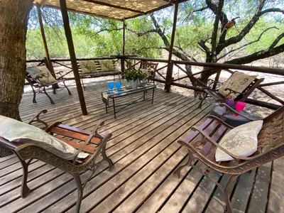 a wooden deck with chairs and a table and a tree at Milkwood Holiday Home in Marloth Park