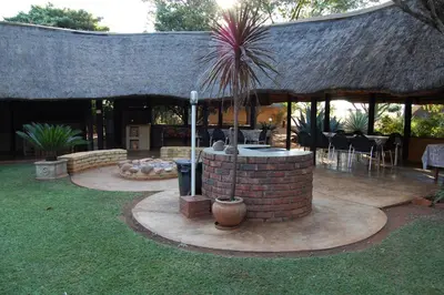a patio with a brick fire pit with a roof at Gallery Inn in Bela-Bela
