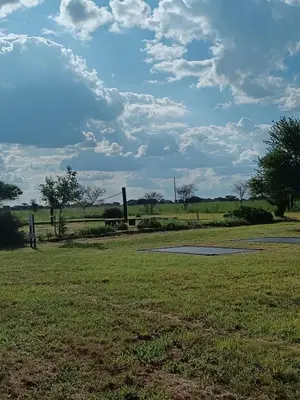 a grassy field with a sky with clouds at Gallery Inn in Bela-Bela