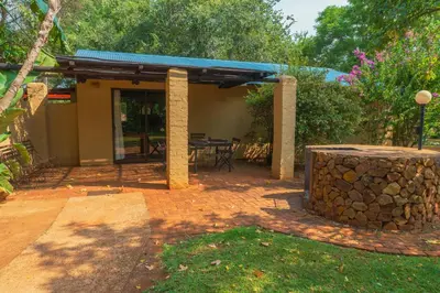 a patio with a table and a stone wall at Gallery Inn in Bela-Bela