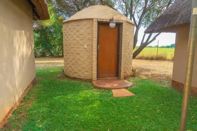 a brick outhouse with a door in the grass at Gallery Inn in Bela-Bela