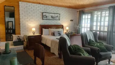 a bedroom with a bed and two chairs at Tranquility Guest House in Sabie
