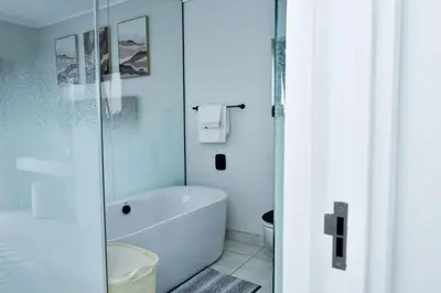 a bathroom with a tub and a glass shower at The Waterfall Retreat in Midrand