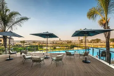 a deck with chairs and umbrellas next to a pool at The Waterfall Retreat in Midrand