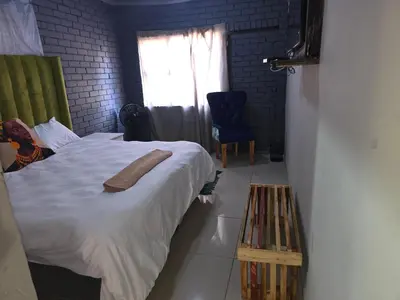 a bedroom with a bed and a chair and a window at EzekMary Res in Polokwane
