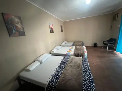 a room with two beds in it with a chair at Happy time accommodation in Phalaborwa