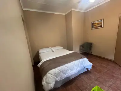 a small bedroom with a bed and a chair at Happy time accommodation in Phalaborwa