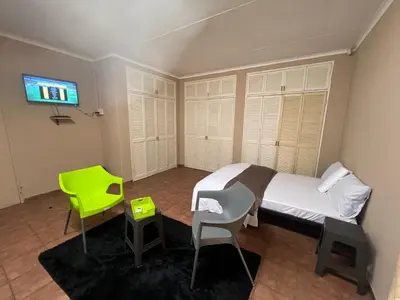 a bedroom with a bed and a green chair at Happy time accommodation in Phalaborwa