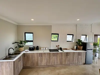 a kitchen with wooden cabinets and a sink at Escape Pretoria East Luxury Villa in Tierpoort