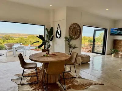 a living room with a wooden table and chairs at Escape Pretoria East Luxury Villa in Tierpoort