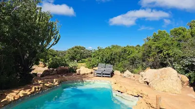 a pool with a bench and a chair and some rocks at Izintaba Private Game Reserve Waterberg in Vaalwater