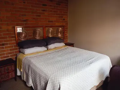 a bedroom with a bed with a brick wall at Midrand Lodge in Midrand