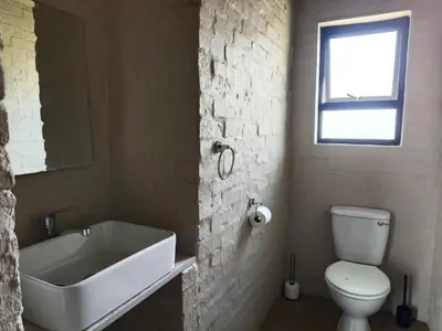 a bathroom with a white toilet and a sink at Olyfburg Herberg in Tierpoort
