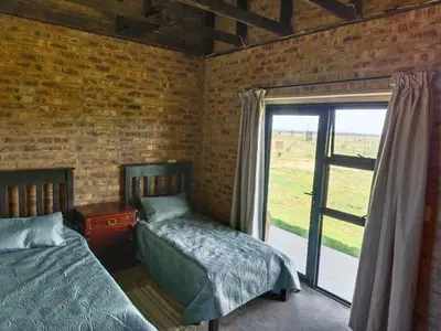 a bedroom with two beds and a sliding glass door at Olyfburg Herberg in Tierpoort