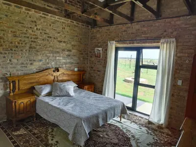 a bedroom with a bed and a large window at Olyfburg Herberg in Tierpoort