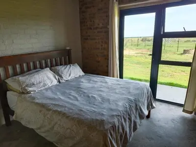 a bed in a room with a large window at Olyfburg Herberg in Tierpoort