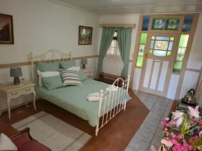 a bedroom with a bed and a table and windows at Plaas Klein Paradys in Blydebos