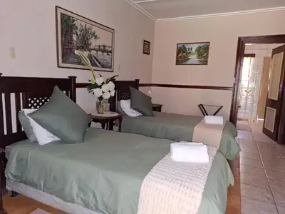 a bedroom with two beds and a vase of flowers at Plaas Klein Paradys in Blydebos