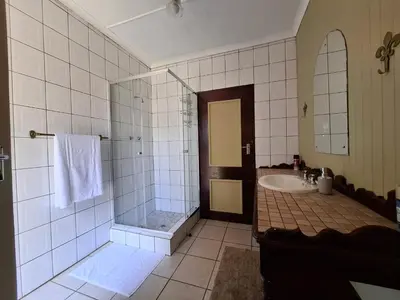 a bathroom with a shower and a tub and a sink at Plaas Klein Paradys in Blydebos