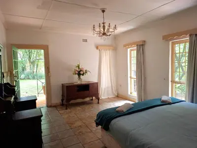 a bedroom with a bed and a table and windows at Plaas Klein Paradys in Blydebos